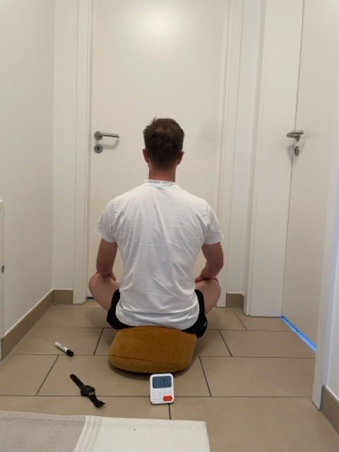 Me sitting in front of a door in our hallway. A kitchen timer showing 1 hour standing behind me, next to my watch, and a Whiteboard marker used to mark a dot on the door.